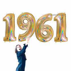 Girl holding 1961 glitter gold number balloons for a 60th birthday or anniversary celebration