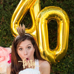 Girl posing with large gold number 40 birthday balloons