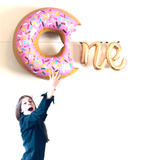 ONE Birthday Balloon banner spelled out with a pink donut balloon plus N + E letter balloons in gold