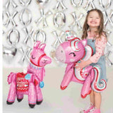 Girl smiling & holding a pink unicorn balloon with a pink llama beside her and silver X & O balloons on the back drop behind her.