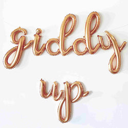 gold letter balloons spelling out giddy up in a cursive script font