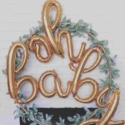 Oh baby script leter balloons in gold in a gold ring with greenery flora 