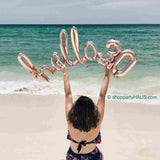 Birthday Girl Holding Rose Gold Hello 30 Foil Balloons  sitting on the beach sand at the ocean for a perfect photo shoot for a 30th birthday!