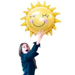 girl holding large sunshine balloon with smiley face