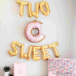 two sweet balloons in gold with a pink donut balloons with a bite out