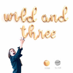 Wild and three cursive letter balloons shown in gold